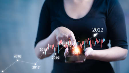 Smartphone with number 2022 concept, Woman touch smartphone and business graph global network of New year 2021 change to 2022 concept, businessman hand touching virtual screen,Technology Processの写真素材