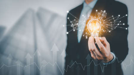 Businessman holding light bulbs, ideas of new ideas with innovative technology and creativity, concept creativity with bulbs that shine glitter, businessman holding illuminated light bulb, innovationの写真素材