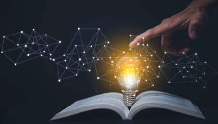 Thinking and creative concept, Light bulb on the Book and light bulb style bokeh vintage dark background,Concept The idea of reading books, knowledge, and searching for new ideas.の写真素材