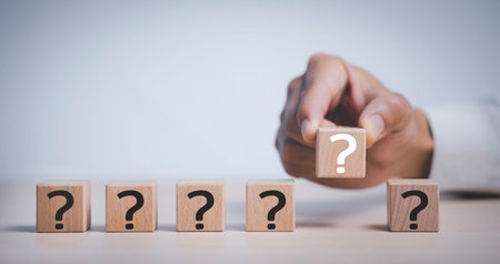 Hand hold Wooden cube block in question mark mean what on cement table background, column of wooden...