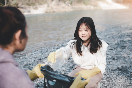 Earth Day concept, Woman and daughter pick up garbage in litter bags, clean-ups in nature to recycling in their communities, clean river and protect environment from pollution, conservation Nature.の写真素材