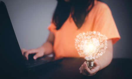 Thinking and creative concept, Asian girl holding the light bulb  in graph Screen Icon of media screen,Technology Process System Business,E-learning Education Internet Technology conceptの写真素材