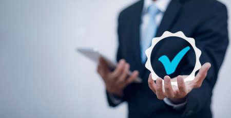 Quality assurance of business services, Businessman Hand shows the sign of the top service Quality assurance in Black background , Guarantee, Standards, ISO certification and standardization concept.の写真素材