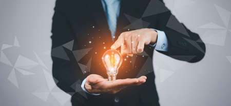 Creativity in the hands of business people idea concept, Businessman holding glowing light bulb with drawing brain and connection line, creative thinking ideas and innovation technology and creativityの写真素材