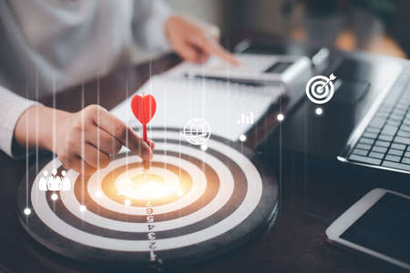 Targeting with marketing business concept, Businesswoman hand holding red dart to the virtual target dartboard, Executive marketing, investment goal and target for business investment concept,の写真素材