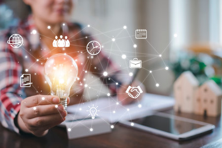 Woman hand hold light bulb with icons work on the desk, Creativity and innovation are keys success. Concept of new idea and innovation with icons and light bulbs, Save the money, Freedom of thought.の写真素材