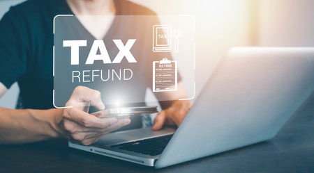 Hand using tablet with bar  TAX REFUND and refund tax of duty taxation business, graphs and chart being demonstrated on the screen media,  tablet pc and selecting tax refund.の写真素材