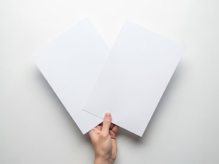 The image depicts a hand carefully holding a paper heart against a white background. The simplicity of the white background emphasizes the paper heart and the hand holding it, creating a minimalist and clean aesthetic. This image is ideal for themes related to love, crafting, and simplicity.の素材