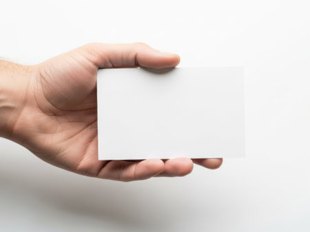 This image features a hand holding a white card against a white background. The simplicity of the image emphasizes the hand and the card, making them the focal points. The white background provides a clean and minimalistic setting, ideal for various applications.の素材