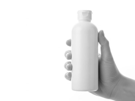 The image features a hand holding a white bottle with a cap against a white background. The bottle appears to be a standard plastic container, possibly for lotion or another liquid product. The hand is positioned to showcase the bottle clearly, with the white background providing a clean and uncluttered setting.の素材