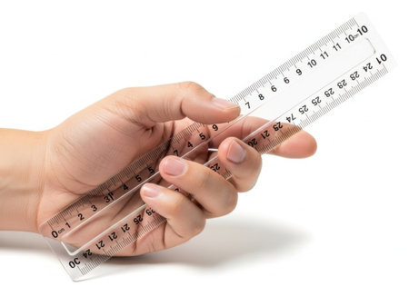 The image depicts a hand holding a transparent ruler against a white background. The ruler displays measurements in both inches and centimeters. The hand is positioned in such a way that the fingers are wrapped around the ruler, with the thumb and index finger holding it securely. The image is clear and SEO-friendly, highlighting the ruler and the hand prominently.の素材