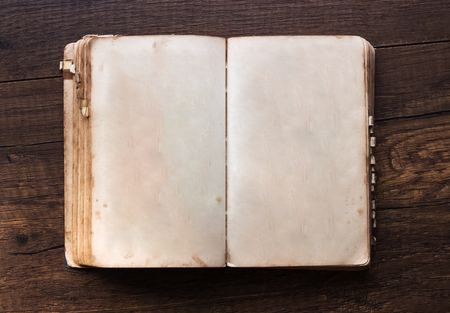 Vintage book, open, on old wooden table.の写真素材