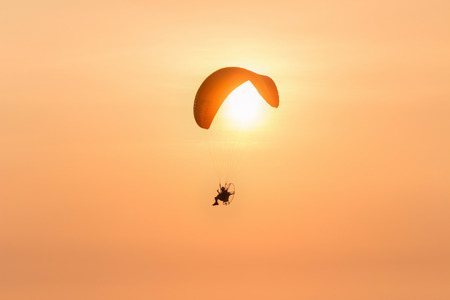 silhouette paramotor with sunset on the orang sky in the evening:ideal use for backgroundの写真素材