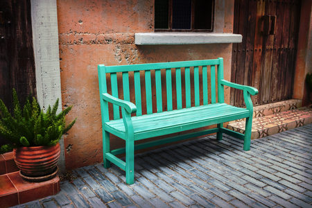 A green bench placed on the sidewalk. By the wallの写真素材
