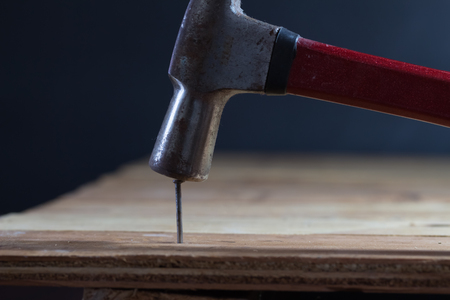 The carpenter uses a hammer to hit the nail on the wooden floor.の写真素材
