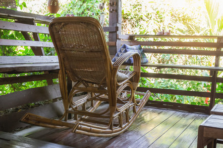 Wicker rocking chair on a wooden house in the old atmosphere in the evening.の写真素材