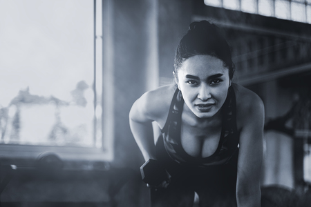 Asian beautiful woman is lifting double in the gym, dark toneの写真素材