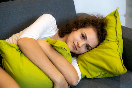 Beautiful European woman sleeping on the sofa, she is staring.の写真素材