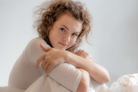 A beautiful European woman sitting in the bedroom in the morning, she woke up.の写真素材