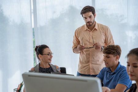A young male supervisor is checking work, talking to his own business team.