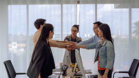 The business team leader calls the team members to join hands to show the team's success, they celebrate by dancing.の写真素材