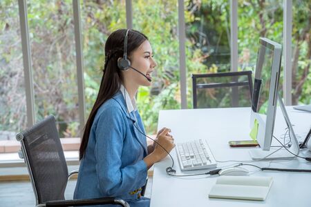 Call Center Asian women are providing business information services in a smile.の写真素材
