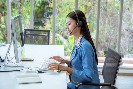 Call Center Asian women are providing business information services in a smile.の写真素材