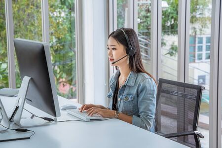 Call Center Asian women are providing business information services in a smile.の写真素材