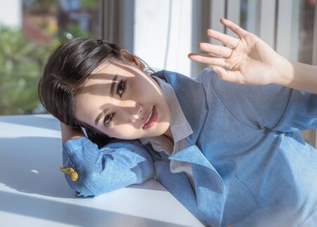 A beautiful Asian woman is raising her hand to prevent light in the eyes.の写真素材
