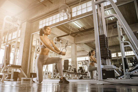 Sexy asian women exercising with a lat pulldown machine to play the arms and shoulder muscles in the...