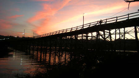 Old wooden bridge over river with sunset on backgroundの写真素材