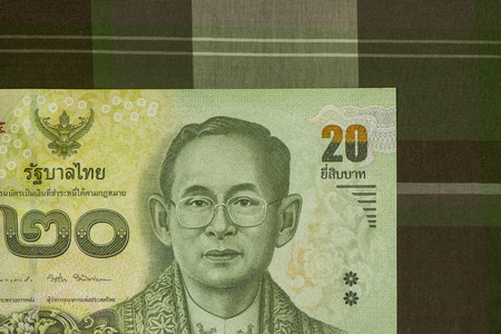 Close up of Thai banknote Thai bath with the image of Thai King. Thai banknote of 20 Thai baht on Green Scottish fabric. Thai currency concepts., Sensitive Focus.の写真素材