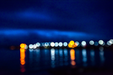 Night twilight blurred light gold bokeh reflecting on the sea surface water abstract background.の写真素材
