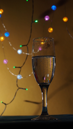 A champagne glass stands on the table. The photo on the background of Christmas light. Still life.の写真素材