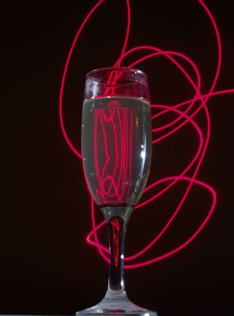 Glass of champagne on the background lights. Illumination of a night club. Still life.の写真素材