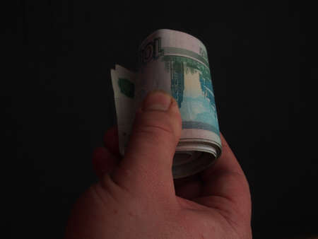 Banknotes in denominations of one thousand rubles in a person's hand. Money rolled up in a tubule. Close up.の写真素材