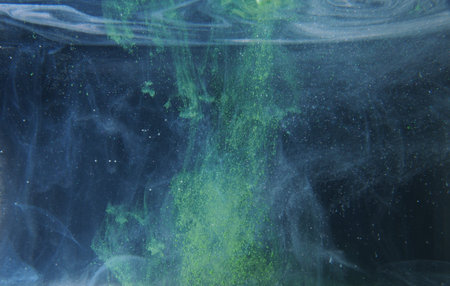 A drop of green paint dissolves in water. An abstract photo. Close up.