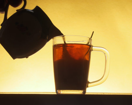 In a transparent glass of tea poured milk from a jug. Tea party. Close up.の写真素材