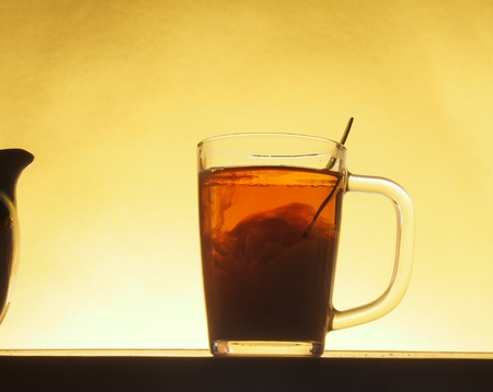In a transparent glass of tea poured milk from a jug. Tea party. Close up.の写真素材