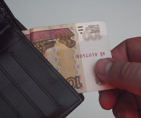 Man pulls out a purse bill of one hundred rubles. Close up.