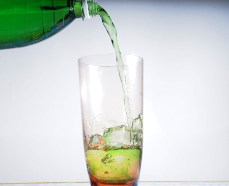 In a tall glass Cup with ice cubes poured green carbonated drink. Still-life.の写真素材