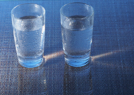 Two glasses of vodka are on the table. The glasses are covered with water droplets. Still-life.