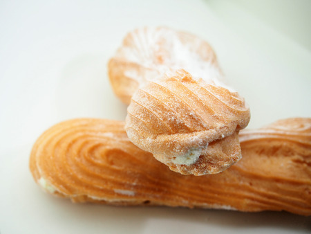 Eclair cake sprinkled with powdered sugar on a white background. Still-life.の写真素材