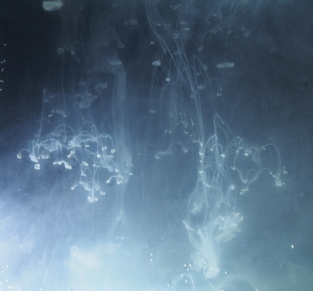 A drop of paint dissolves in water. On black background. Abstract figures.の写真素材