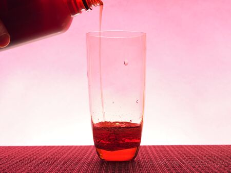 In a clear glass filled with a dark fizzy drink. Photo on a pink background. Still-lifeの写真素材