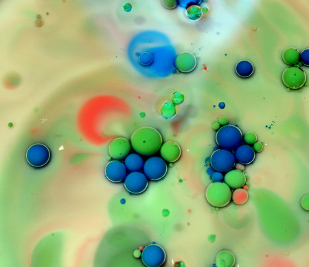 Spheres of white, pink, green, and red color on a multi-colored background. Colored drops in oil....