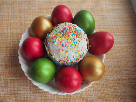 Easter cake and colorful Easter eggs in a white porcelain plate. Raspberry, green and Golden eggs....