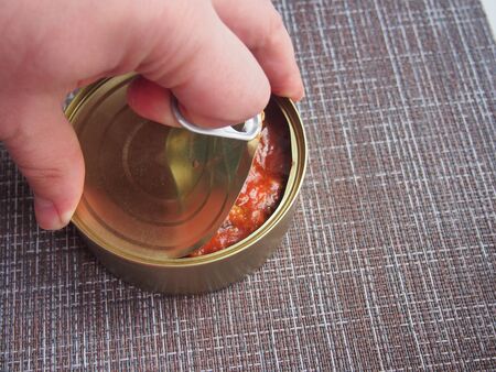 The process of opening a tin can with canned fish in tomato sauce. Still-lifeの写真素材
