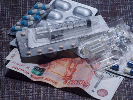 On the table are pills, capsules and ampoules with medicines, a syringe and Russian ruble bills. Close up.の写真素材