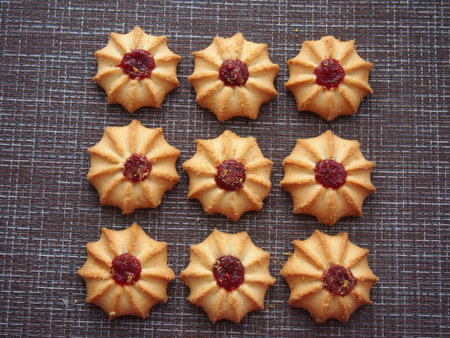 A few pieces of kurabye cookies lie on the brown tablecloth. Close up.